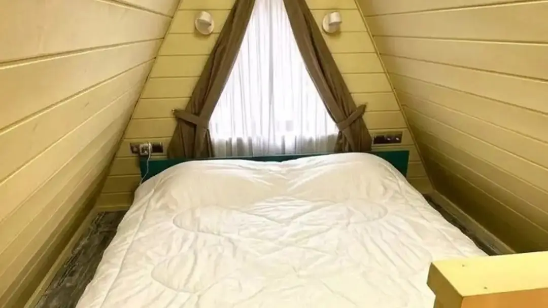 Мансардная спальня под скатной крышей дома